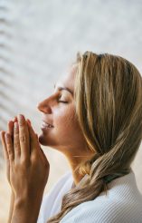 Young woman in prayer, receiving spiritual comfort and faith-based grief support.